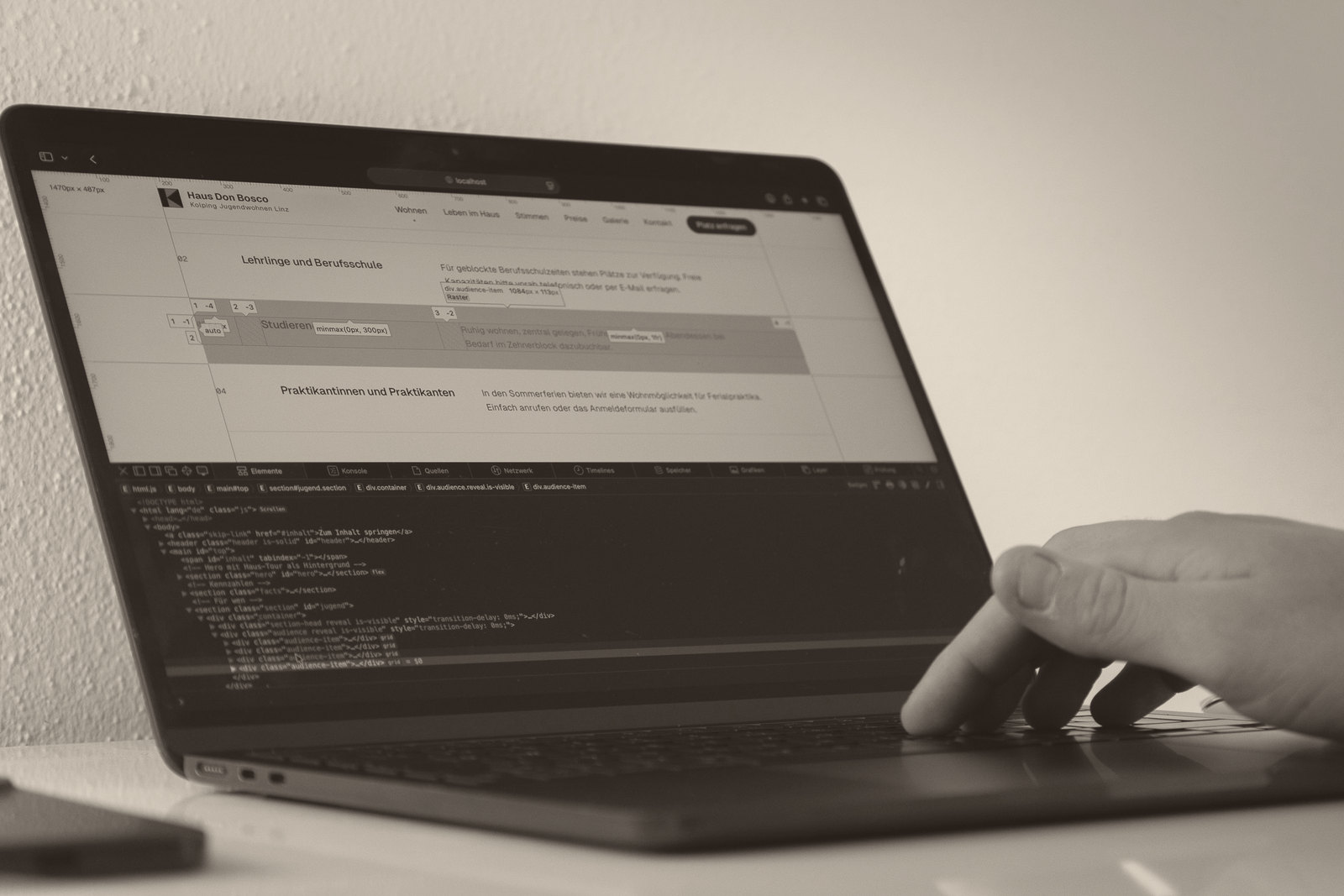 Laptop mit einer Website und geöffneten Entwicklerwerkzeugen, eine Hand auf der Tastatur