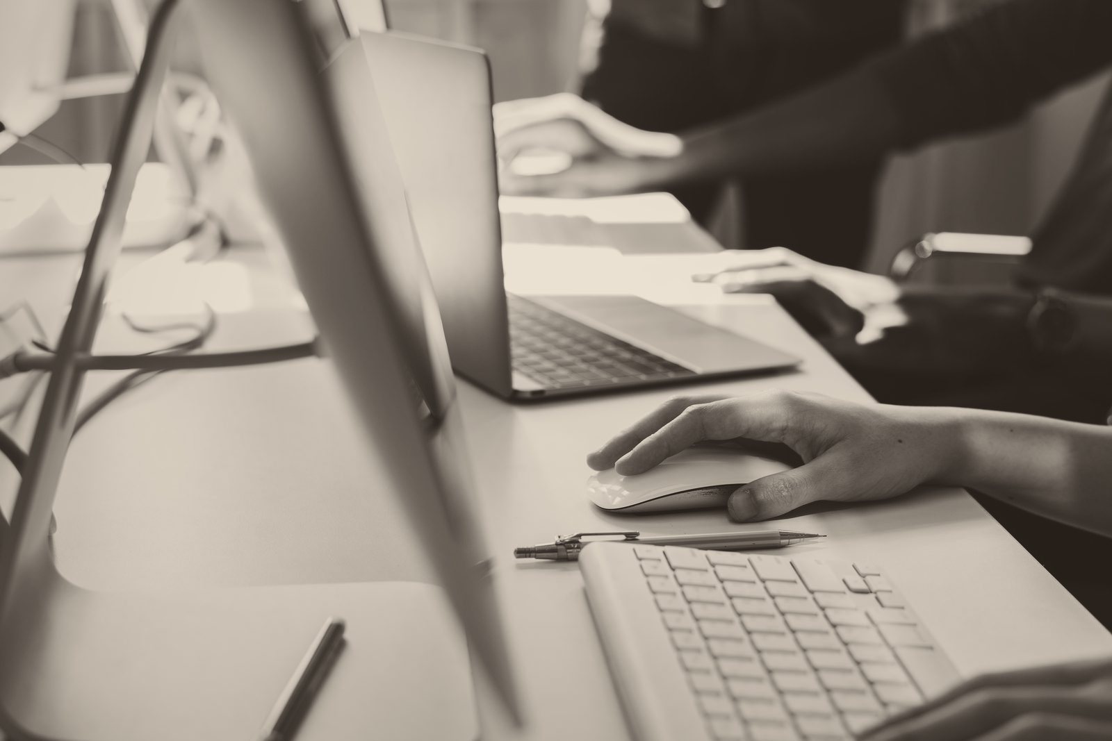 Mehrere Personen arbeiten nebeneinander an Rechnern und Laptops